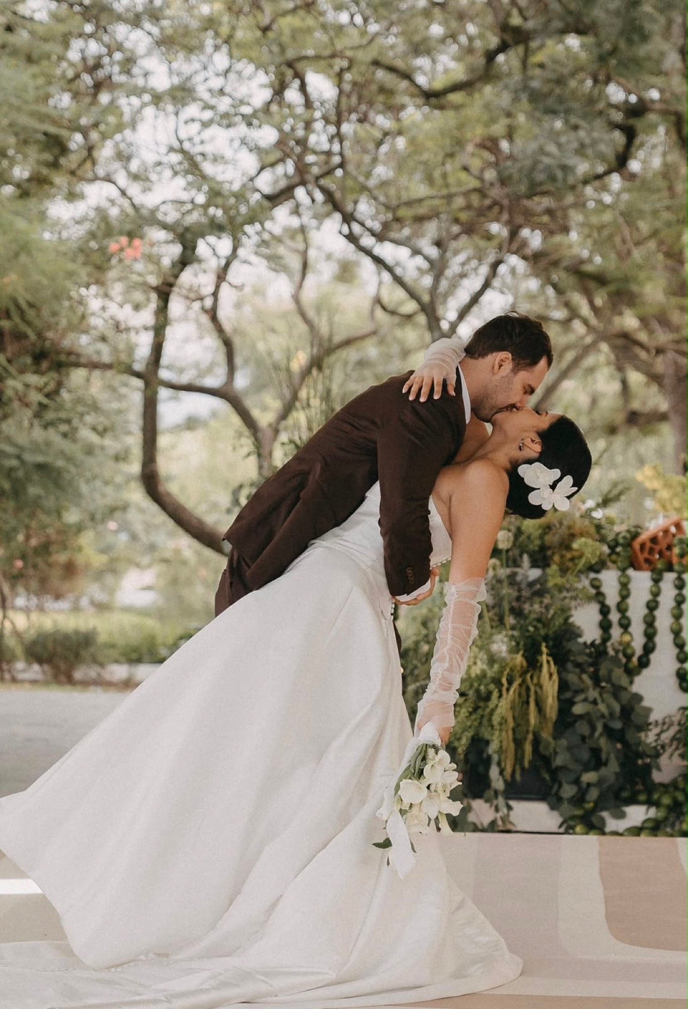 Novios besándose durante su boda, rodeados de jardín
